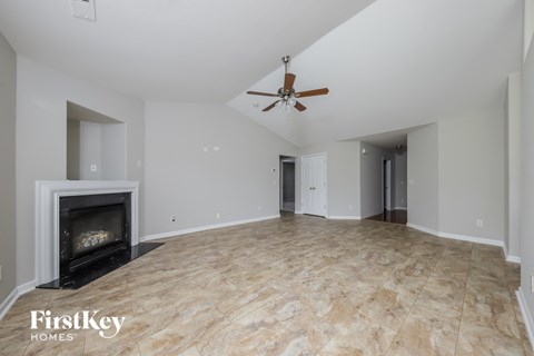 an empty living room with a fireplace and a ceiling fan