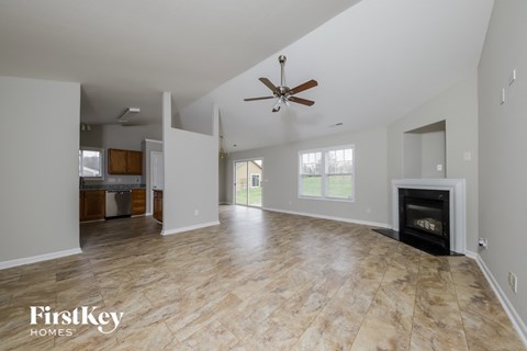 an empty living room with a fireplace and a ceiling fan