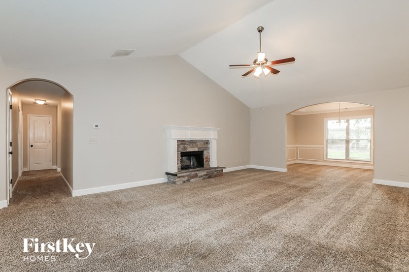 an empty living room with a fireplace and a ceiling fan