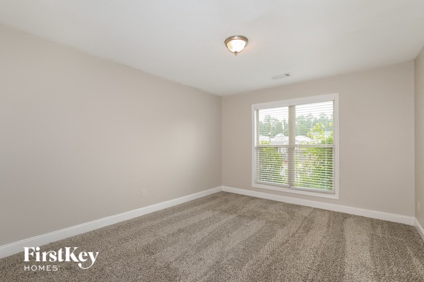 a bedroom with carpet and a large window