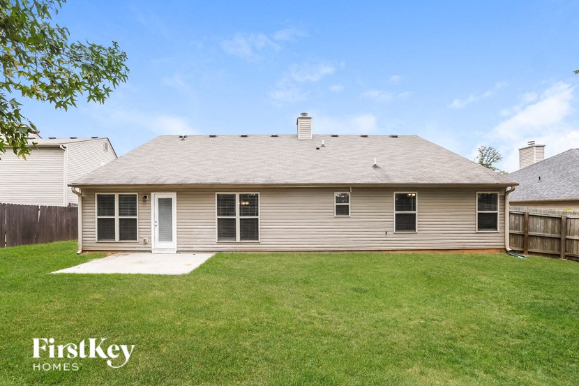 a small house with a grassy yard and a wooden fence