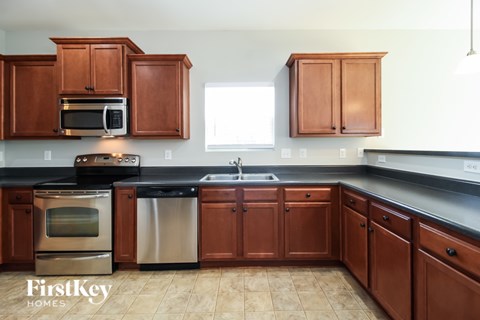 A kitchen with brown cabinets and a black countertop.