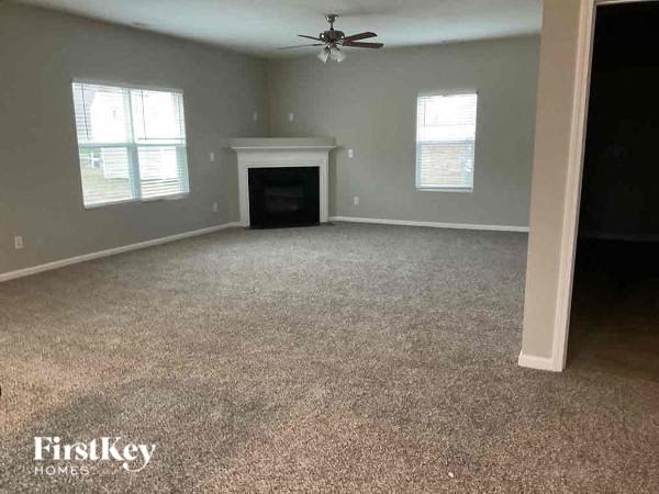 A spacious room with a fireplace and a ceiling fan.