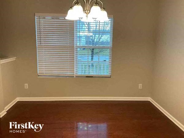 A room with wooden floors and a window with blinds.