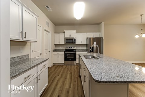 A kitchen with white cabinets and a granite countertop.