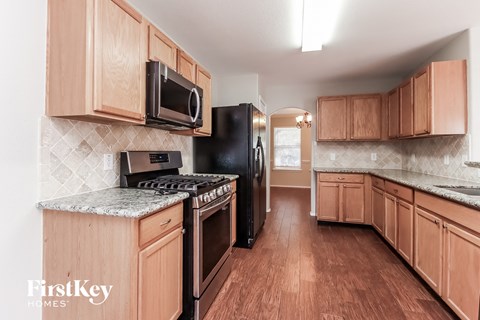 A kitchen with wooden cabinets and a black refrigerator.