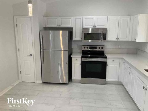 a kitchen with white cabinets and a stainless steel refrigerator