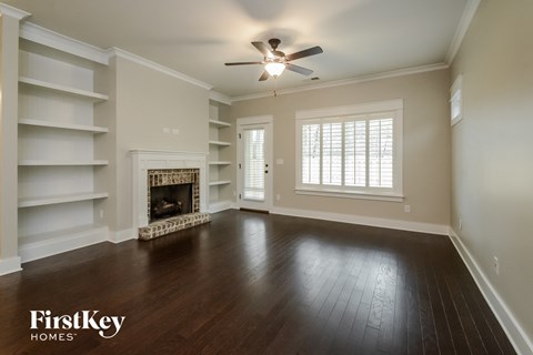 A spacious room with a fireplace and a ceiling fan.