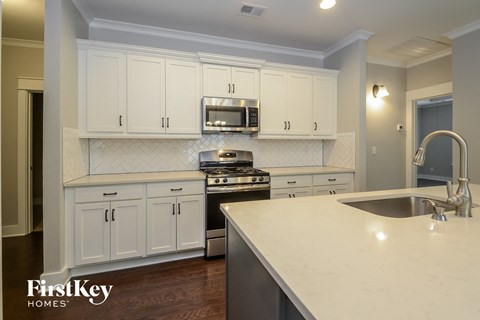A kitchen with white cabinets and a stove top oven.