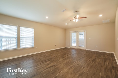the spacious living room with hardwood flooring and a ceiling fan
