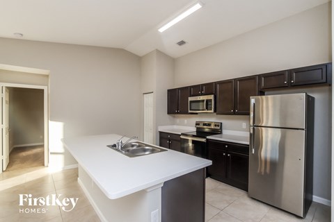 A kitchen with a white counter top and a stainless steel refrigerator.
