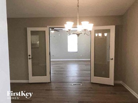a empty living room with two doors and a chandelier