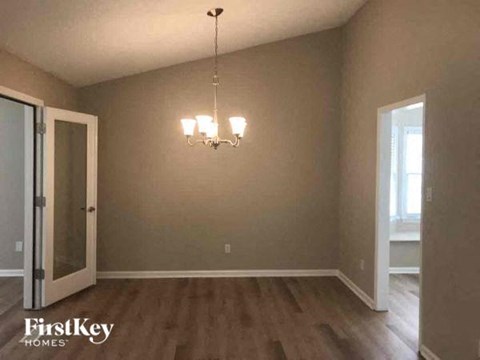 a empty living room with a chandelier and a door
