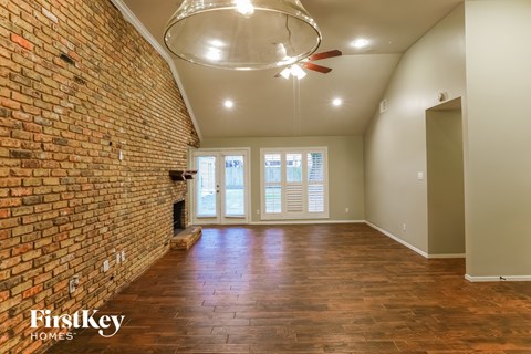 an empty living room with a brick wall and a ceiling fan