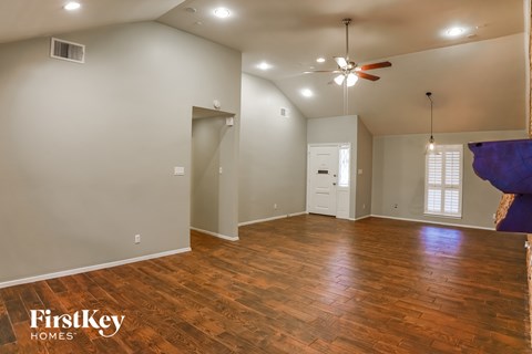a clean and empty living room with wood floors and a ceiling fan
