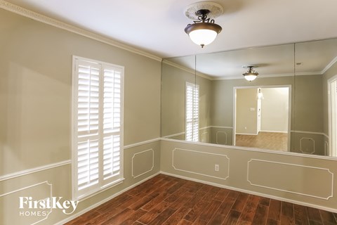 an empty dining room with a large mirror and wood floor