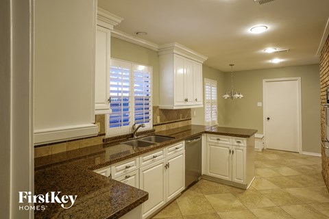 a white kitchen with granite counter tops and white cabinets
