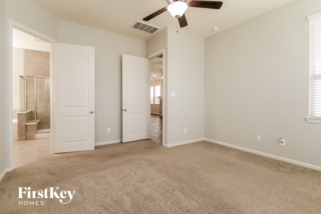 an empty living room with a ceiling fan and a closet