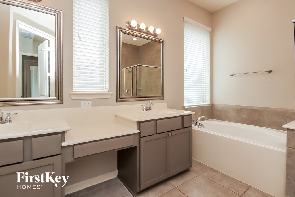 a bathroom with two sinks and a tub and a mirror