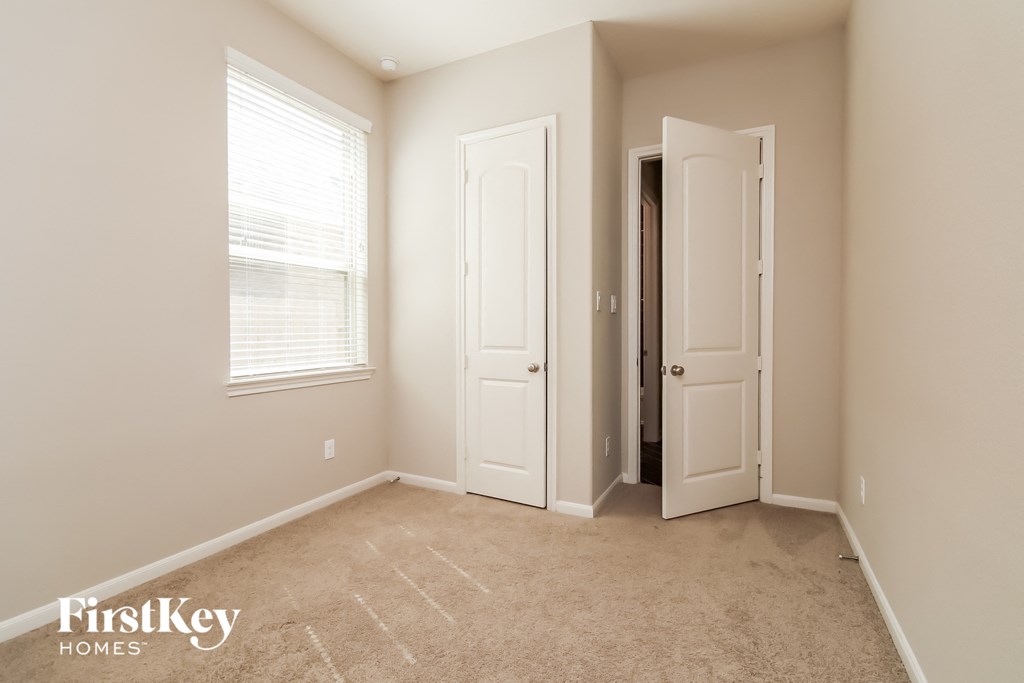 a bedroom with a carpeted floor and two doors and a window