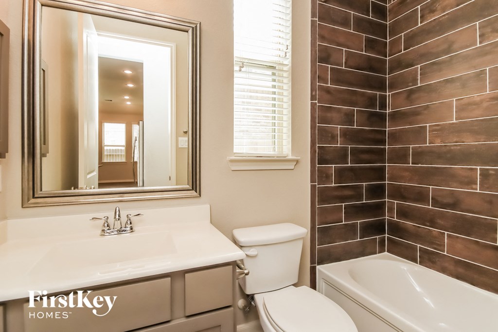 a bathroom with a toilet sink and mirror and a tub