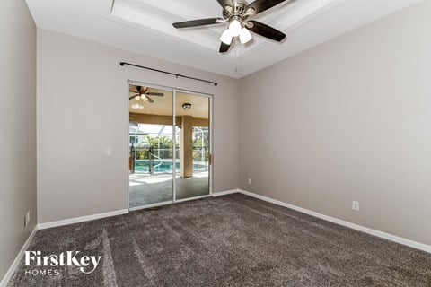 the living room of a house with carpet and a ceiling fan