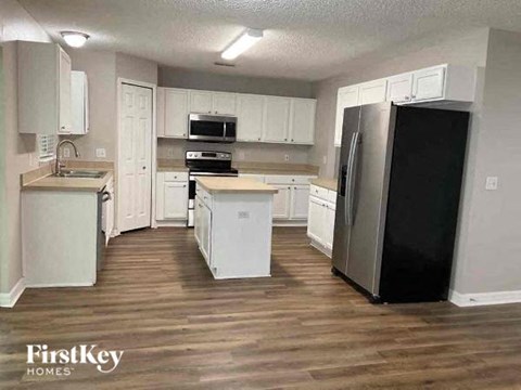 a kitchen with white cabinets and a black refrigerator
