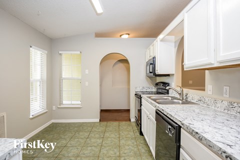 A kitchen with a sink, stove, and cabinets.