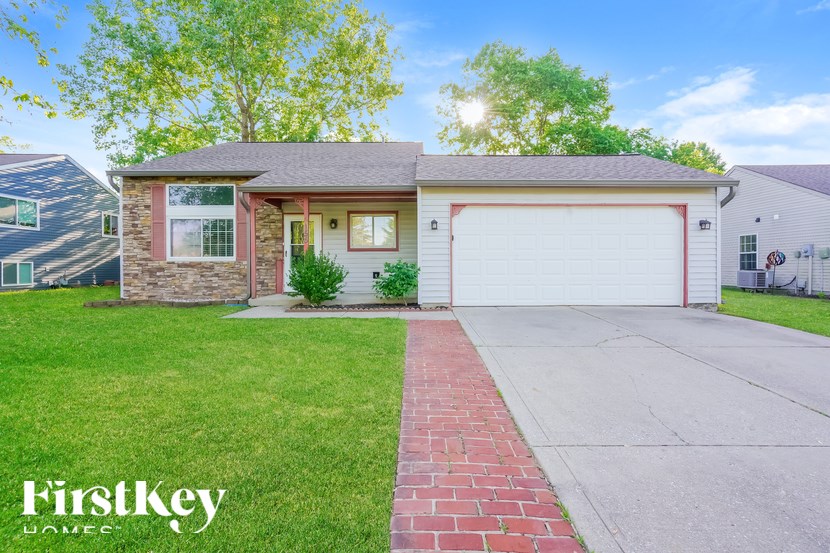 A house with a red brick pathway leading to a white garage door.