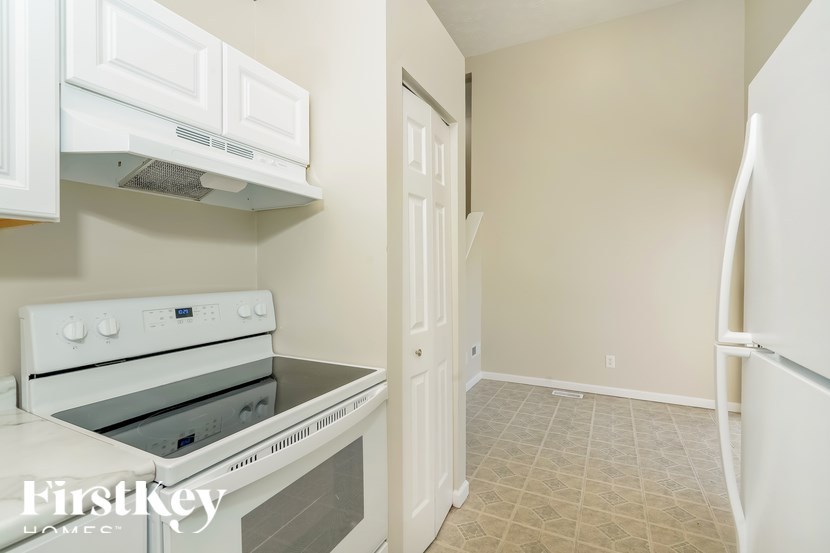 A white oven and cabinets in a kitchen with a tile floor.