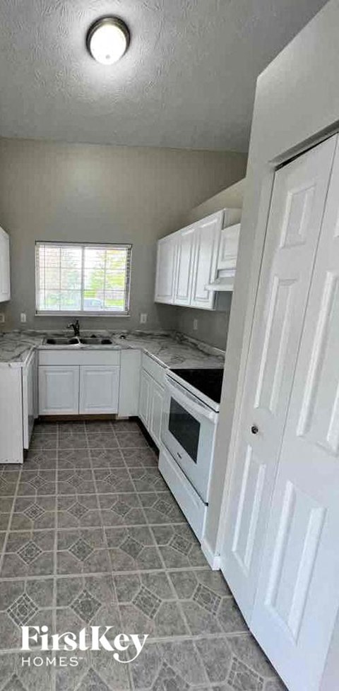 A kitchen with white cabinets and a tile floor.