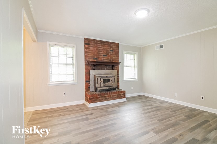 A room with a brick fireplace and wooden floors.