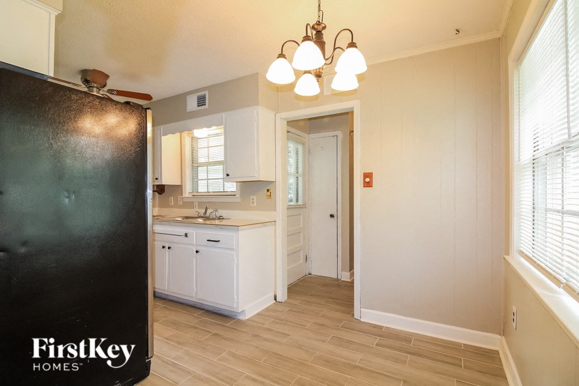 A kitchen with a black refrigerator and wooden floors.