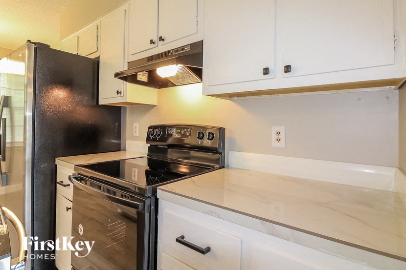 A kitchen with a black fridge and white cabinets.