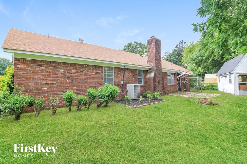 A brick house with a chimney and a small garden in front.