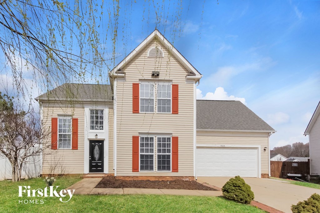 a white house with red shutters and a driveway