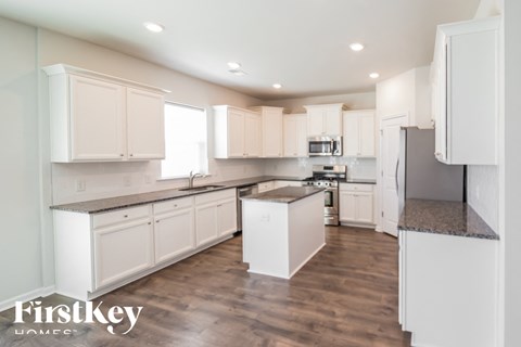 A kitchen with white cabinets and a wooden floor.
