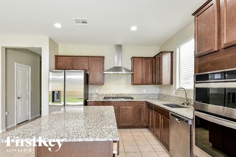 A kitchen with brown cabinets and a granite countertop.