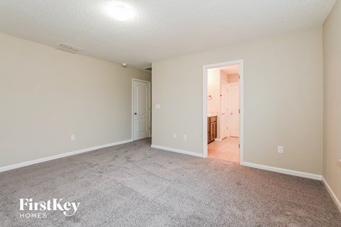 a spacious living room with carpet and a door to the kitchen