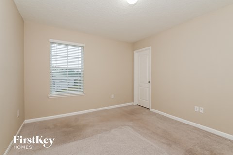 a bedroom with beige carpet and a white door and window