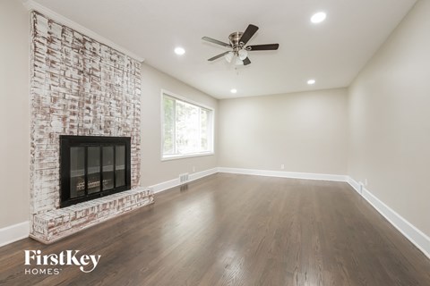 a living room with a brick fireplace and a ceiling fan