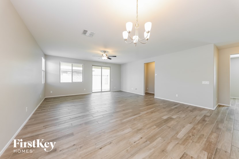 A spacious room with wooden flooring and a chandelier.