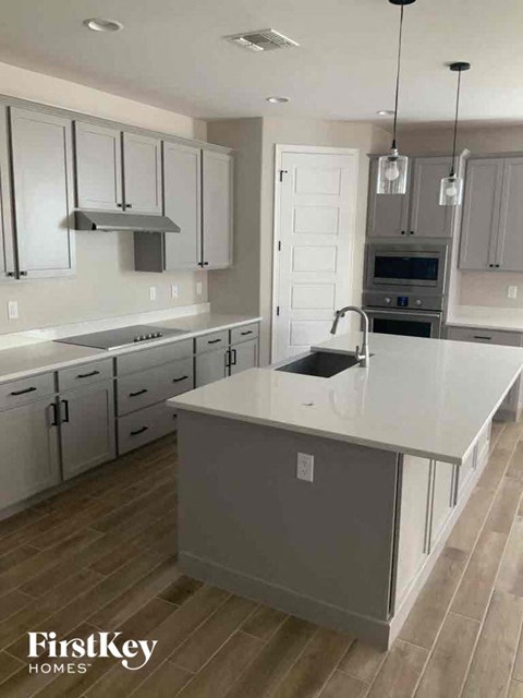 A kitchen with a white countertop and wooden floors.