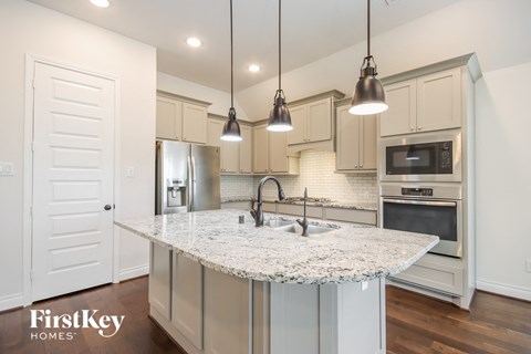 a kitchen with white cabinets and a marble counter top