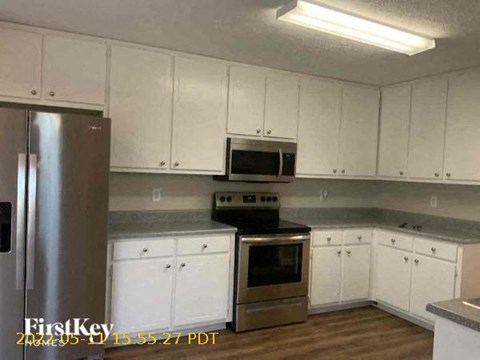 A kitchen with white cabinets and a stainless steel refrigerator.