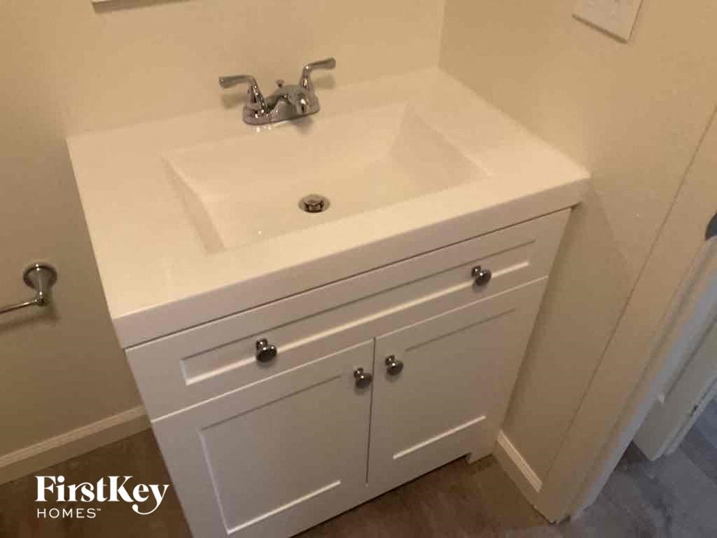 a white sink in a bathroom with a white cabinet and a mirror