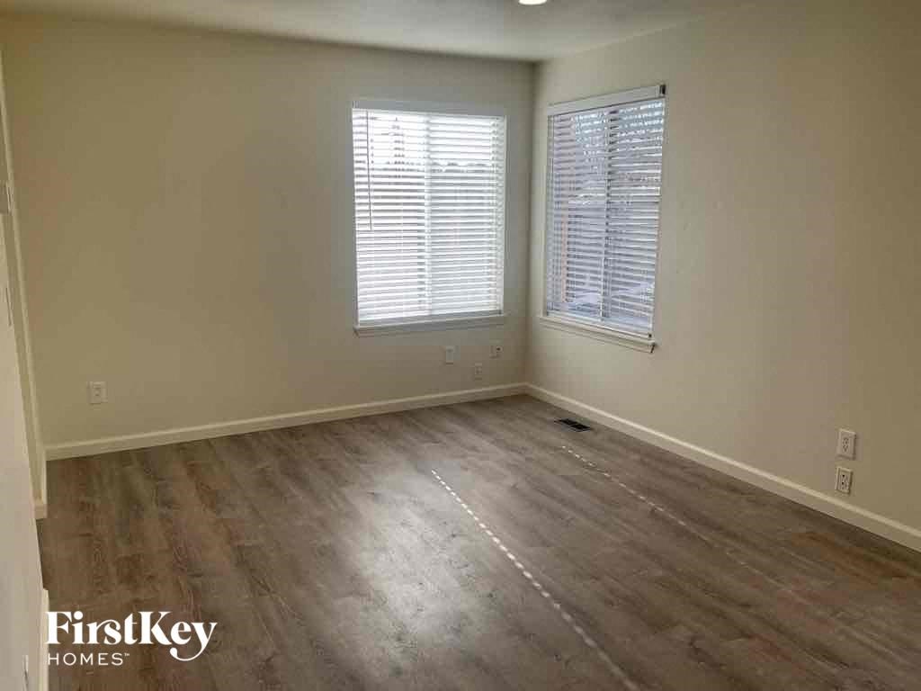 an empty living room with wooden floors and two windows