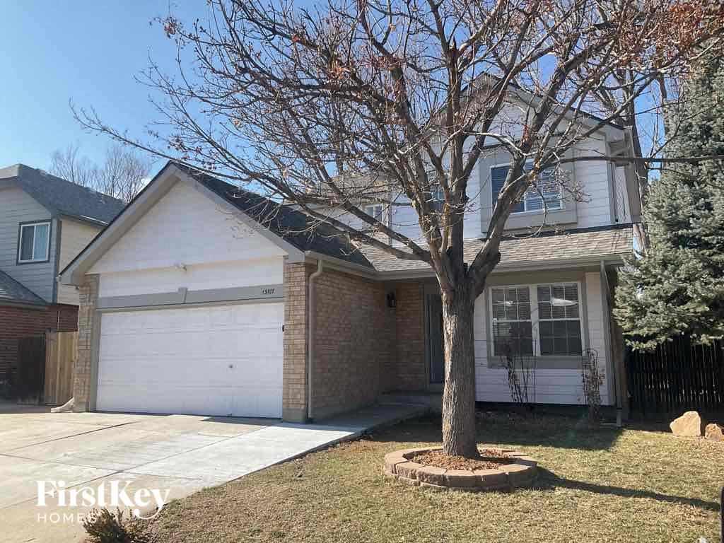 the front of a house with a tree in the front yard