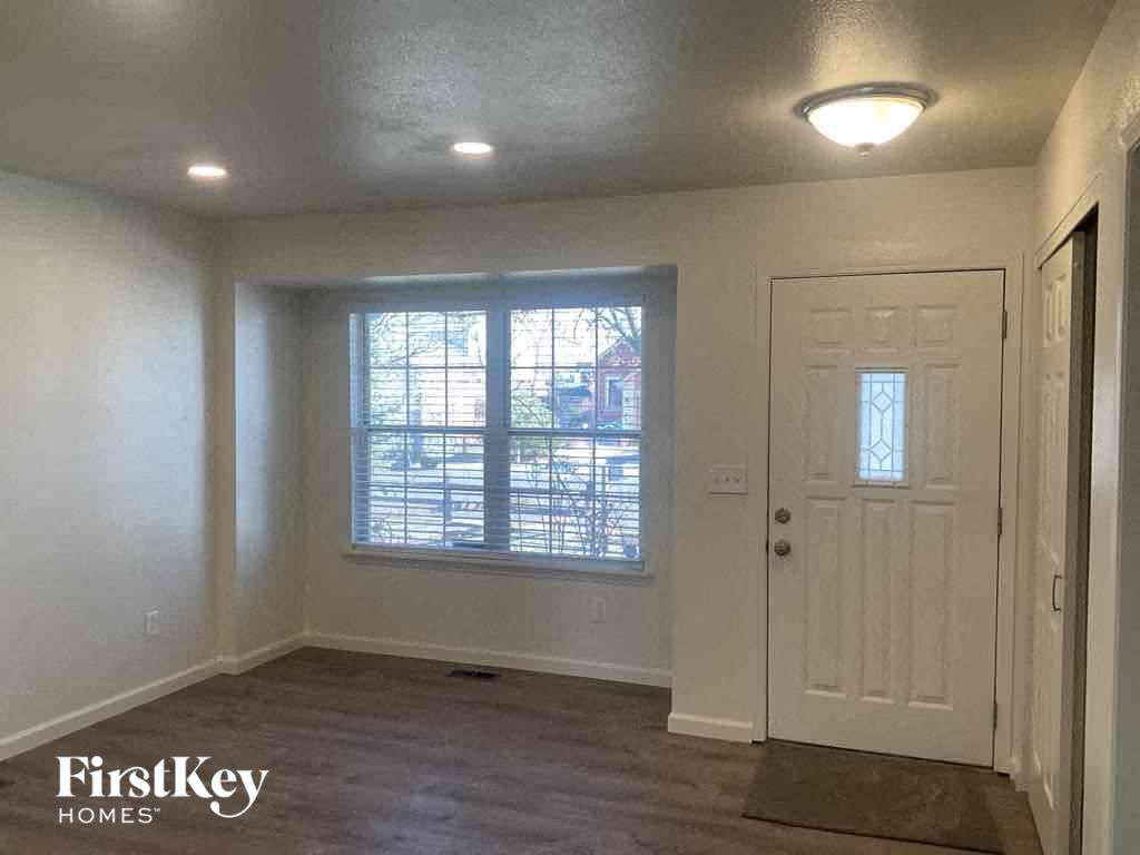 an empty living room with a white door and a window