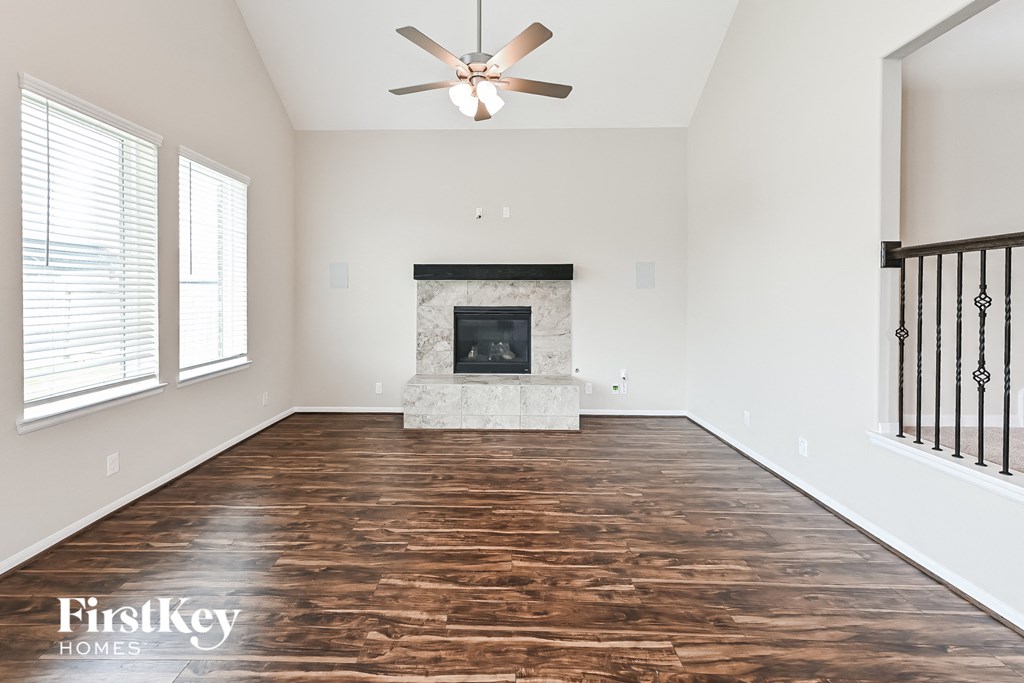 an empty living room with a fireplace and a ceiling fan